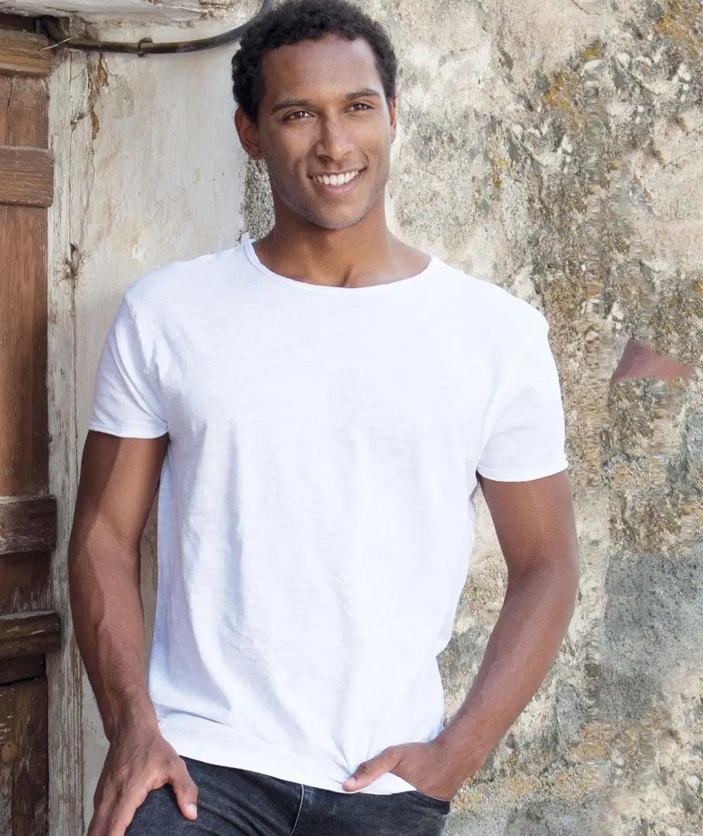 Uomo indossa t-shirt bianca in cotone slub, stile streetwear, fondo urban rustico