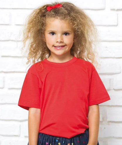 Bambina con t-shirt rossa in cotone e gonna nera, stile streetwear urban, sfondo muro bianco.