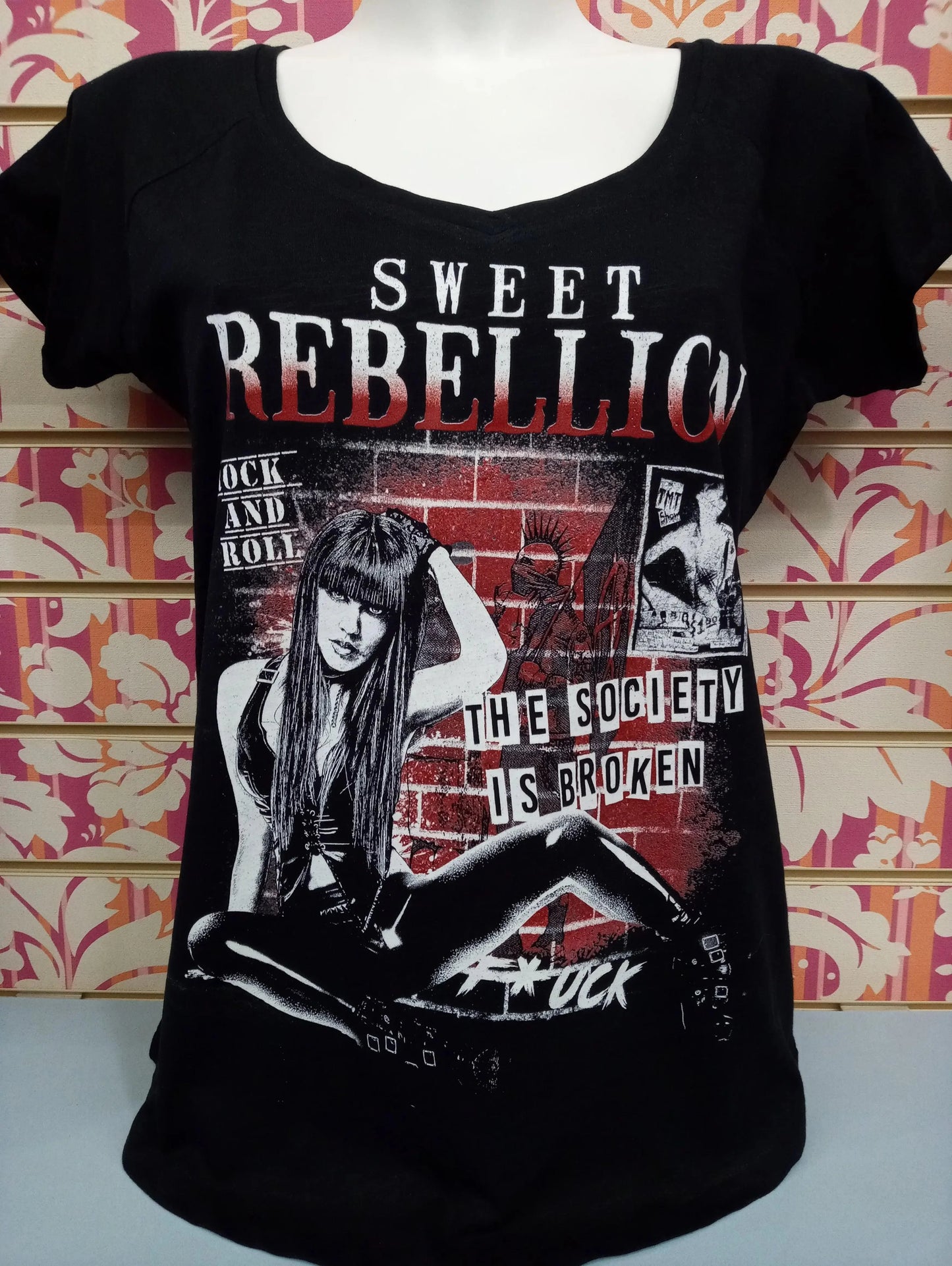 T-shirt donna streetwear nera con stampa grafica a tema ribelle, dettagli rock, mattoni rossi e scritte bianche.