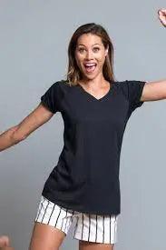 Donna in street style con t-shirt nera, pantaloncini bianchi a righe, look urban casual.