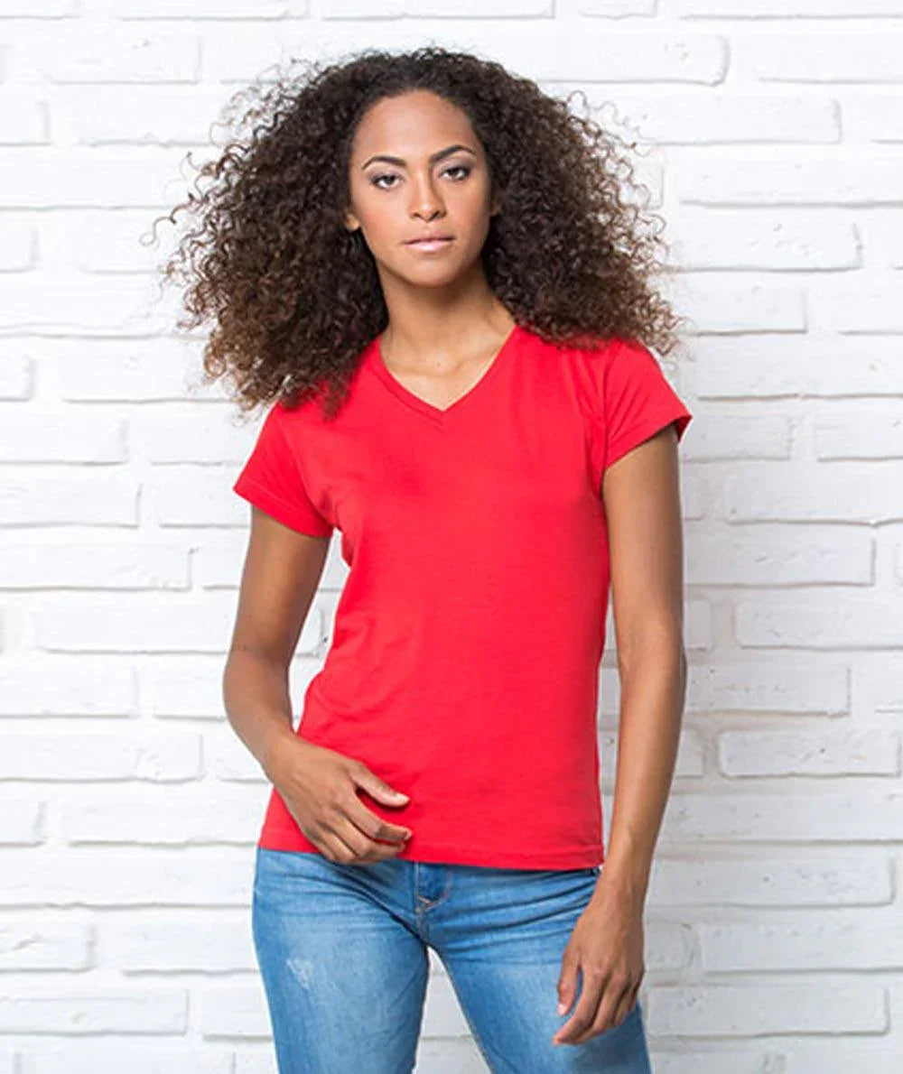 Donna con t-shirt rossa in cotone stile streetwear, jeans chiari, sfondo muro bianco