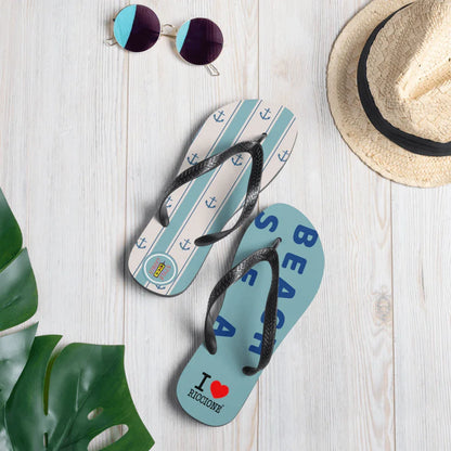 Infradito streetwear azzurre con stampe ancora e scritte, stile urban, su tavola chiara di legno.