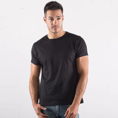 Uomo con t-shirt nera in cotone e jeans, stile streetwear urban, sfondo bianco minimalista.
